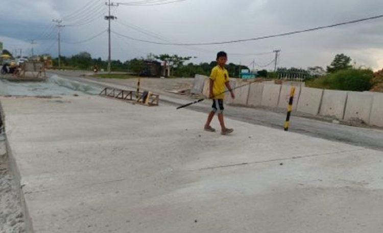 Seorang anak berjalan di ruas jalan yang kini tampak mulus. (Pemprov)