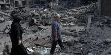 Warga Gaza melewati puing-puing bangunan yang runtuh dihantam rudal zionis Israel. (EPA)